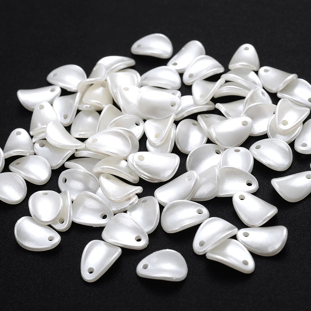 A pile of small, white imitation pearl flower spacer beads for DIY jewelry.