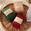 Three skeins of natural colored cotton yarn are displayed on a woven tray.