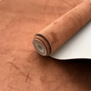 Roll of brown suede auto headliner fabric with foam backing resting on a surface.