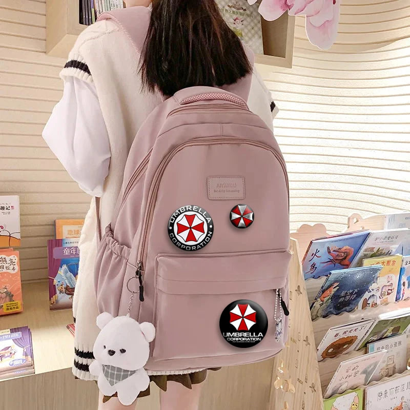 A pink cartoon anime brooch pin is attached to a light pink backpack worn by a person.