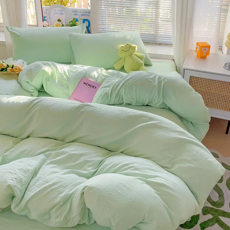 A light mint green cotton bed linen set with a fluffy duvet and pillows, featuring a yellow stuffed toy.