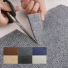 A hand is using scissors to cut a gray carpet tile, next to a swatch of various colored square tiles.