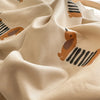 A close-up of beige fabric with a repeating pattern of orange and black dog silhouettes, showing soft folds.