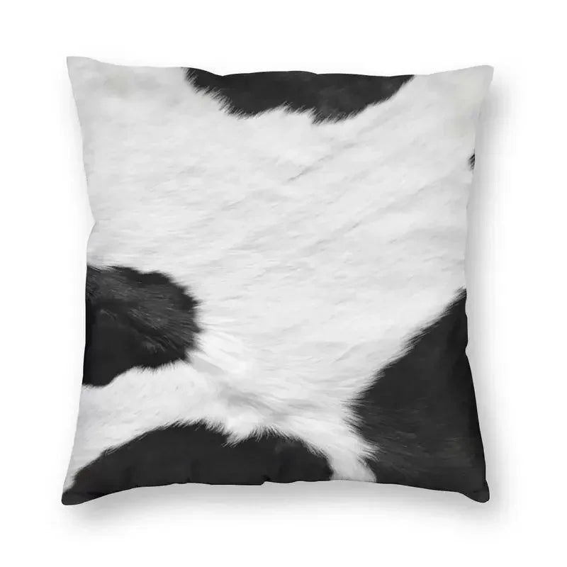 A square cushion cover made of faux fur cowhide print featuring black and white patches.