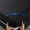 A hand is holding a black quilted mattress protector with the Healthy Sleep brand label visible.