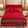 A vibrant red quilted bed skirt with intricate embroidery and fringe, displayed on a luxurious bedroom set.