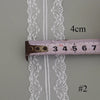White floral hollow-out lace ribbon measured against a ruler.