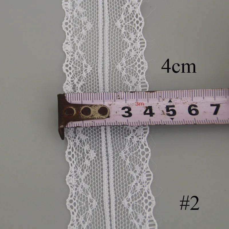 White floral hollow-out lace ribbon measured against a ruler.