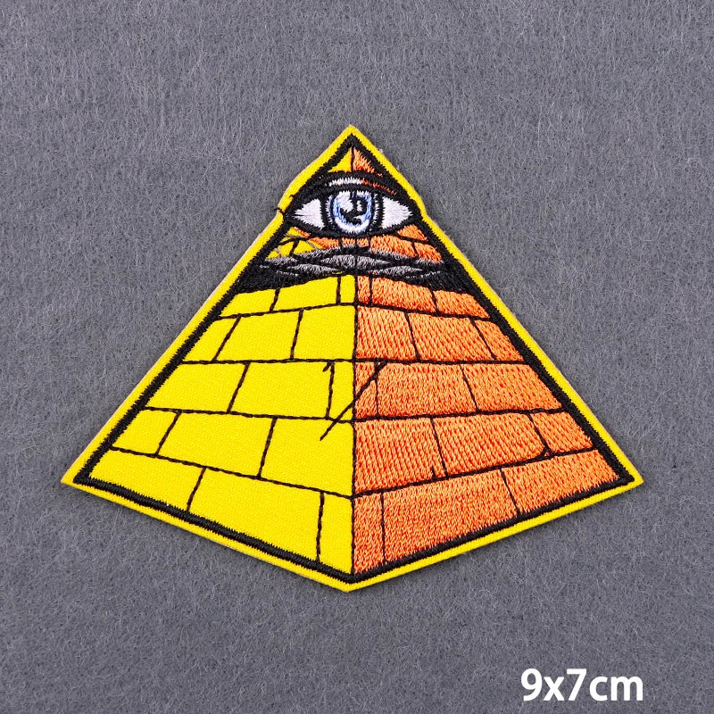 A triangular embroidery patch featuring an eye design with yellow and orange checkered patterns.