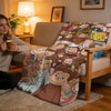 A plush throw blanket featuring various illustrations of Curious George characters draped over a light-colored sofa.