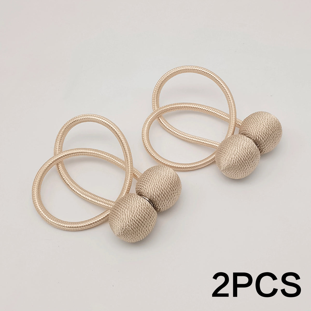 Two gold-toned minimalist magnetic ball curtain tiebacks with thin loops and spherical balls.