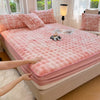 A pink luxury faux rabbit fur fitted sheet set is displayed on a bed, with natural light and a lamp in the background.
