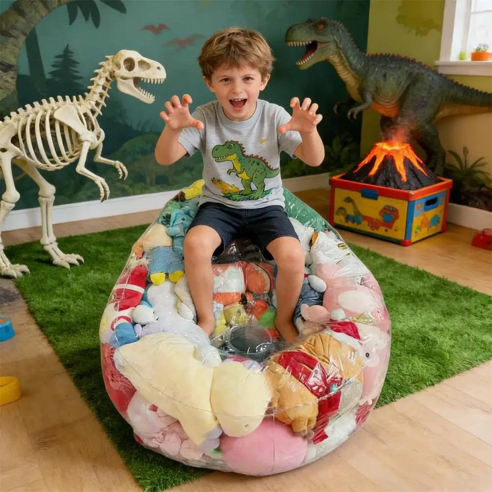 A child sits inside a large, colorful inflatable storage bag filled with various plush toys in a room decorated with dinosaur