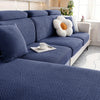 A deep blue woven sofa seat cushion cover with a textured pattern and a white decorative pillow on a light-colored sofa.