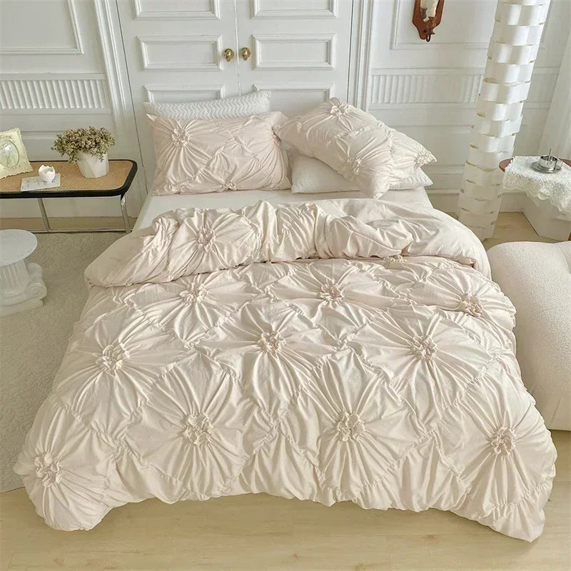 A light pink pinch pleat duvet cover set displayed on a bed with white paneling and pillows.