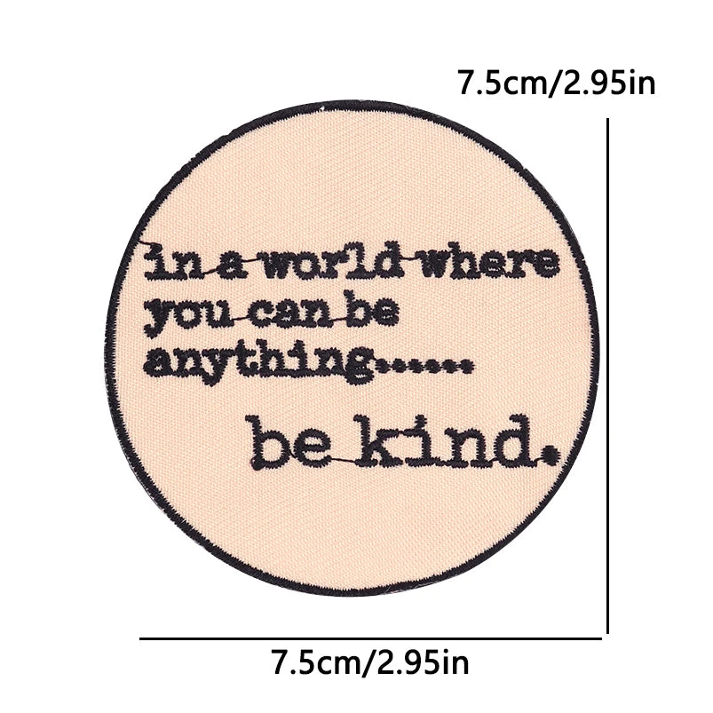 A circular embroidery patch with text that reads in a world where you can be anything be kind