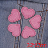 Five pink glitter heart star iron-on patches are laid out on a denim fabric.