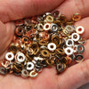 A handful of small, round acrylic flat spacer beads in various gold and silver tones held in a person's hand.
