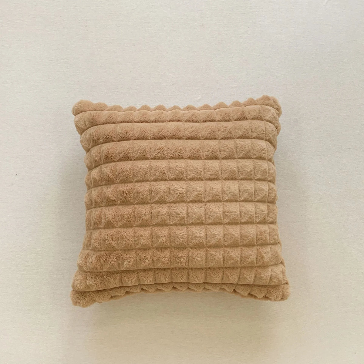 A rectangular, textured beige plush winter throw pillow cover.