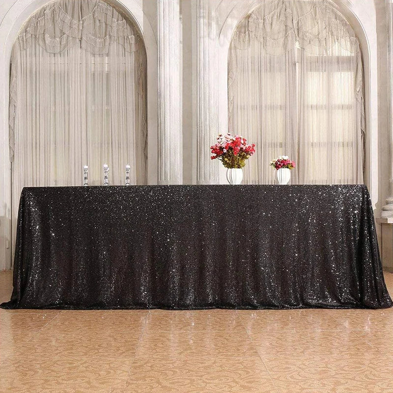 Black sequin glitter tablecloth draped on a table in a bright, arched room with sheer curtains.