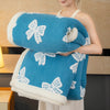 A woman holds a thick blue and white patterned jacquard lambswool blanket against her chest.