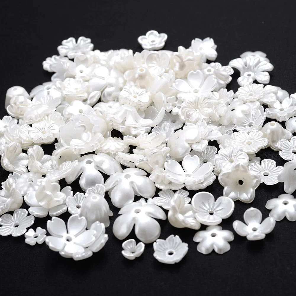 A pile of small, white imitation pearl flower spacer beads for DIY jewelry.