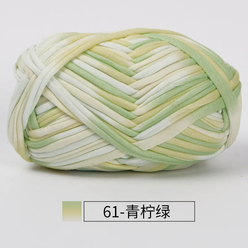 A ball of hand-dyed fabric strip yarn in pale green and cream colors, coiled for crochet or knitting.