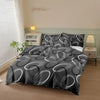 A black and white patterned printed quilt set displayed on a bed with a light green wall and natural light.