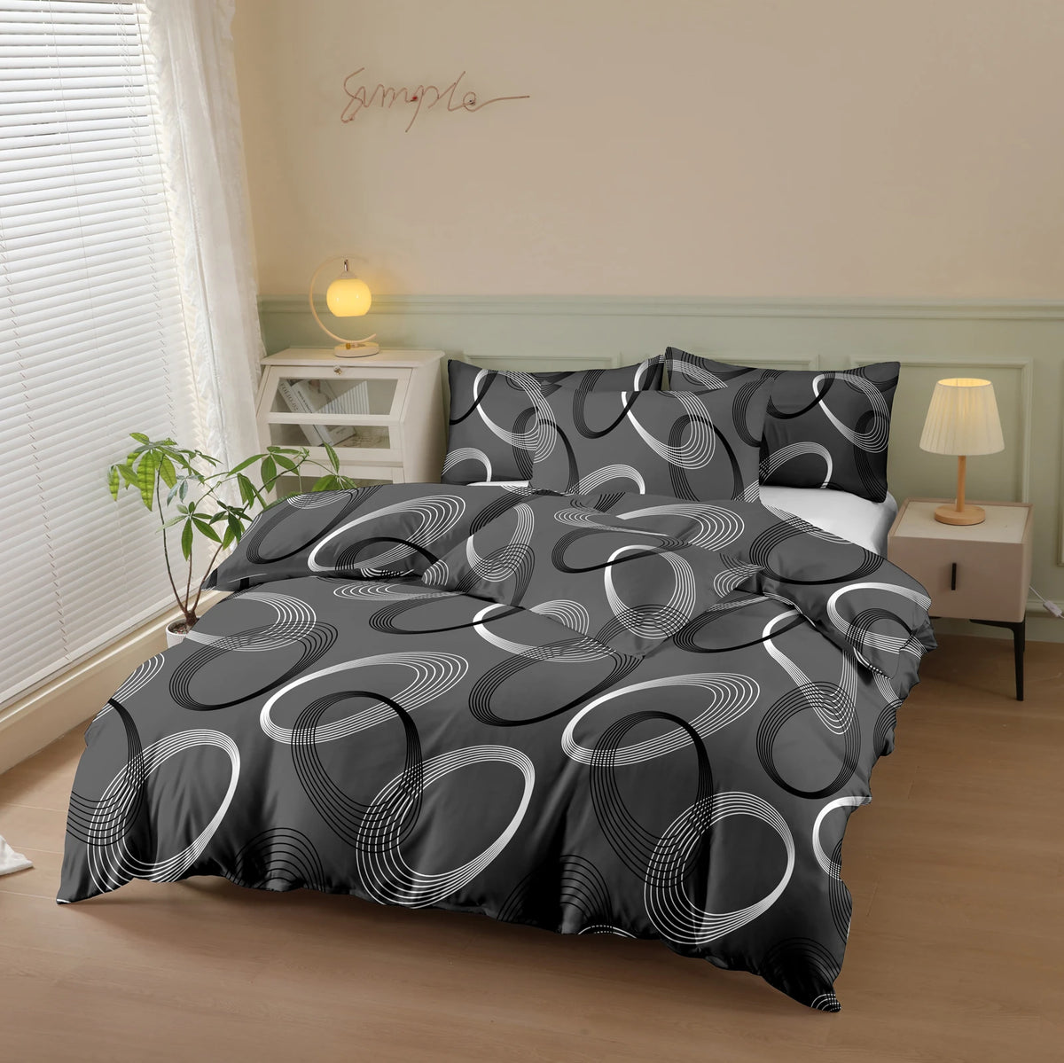 A black and white patterned printed quilt set displayed on a bed with a light green wall and natural light.