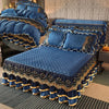 A navy blue velvet bed skirt with gold trim and diamond pattern is displayed on a bed.