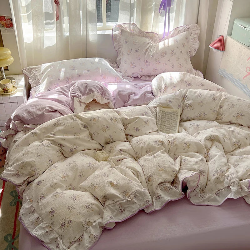 A floral bedding set featuring light pink and cream patterned duvet covers and pillows on a bed.
