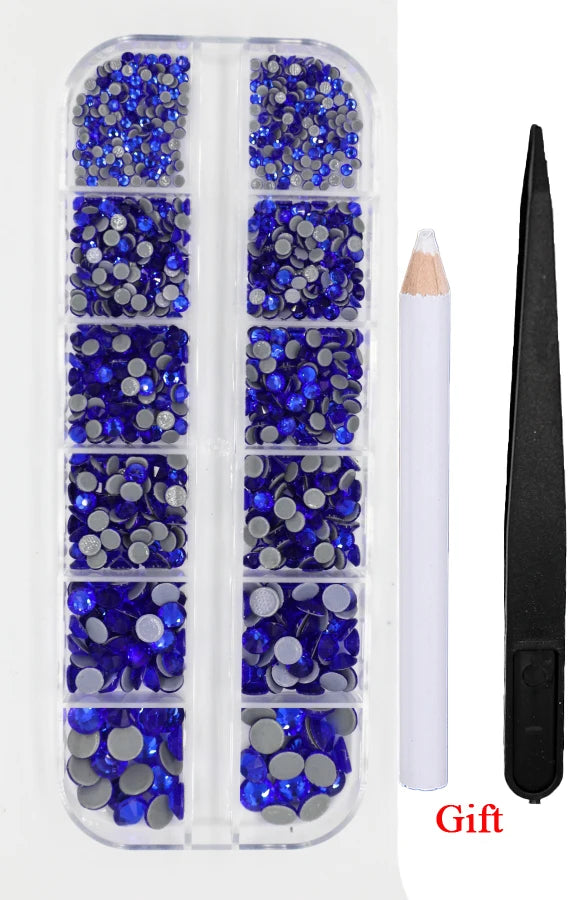 A clear plastic container holds various shades of blue and silver crystal rhinestones for crafting or jewelry making.