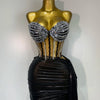 A gold mannequin displays a sparkly diamond two-piece performance set featuring embellished cups and a black draped skirt.