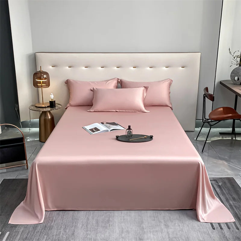 Pink luxury bamboo flat sheets displayed on a bed with a padded headboard and bedside decor.