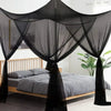 A black mosquito net canopy draped over a wooden bed frame.