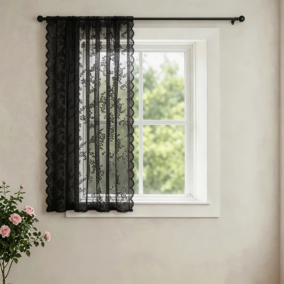 Black lace curtain with a wave border hanging in a white window frame.