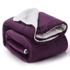 A deep purple sherpa fleece blanket rolled up, showing the soft white lining.
