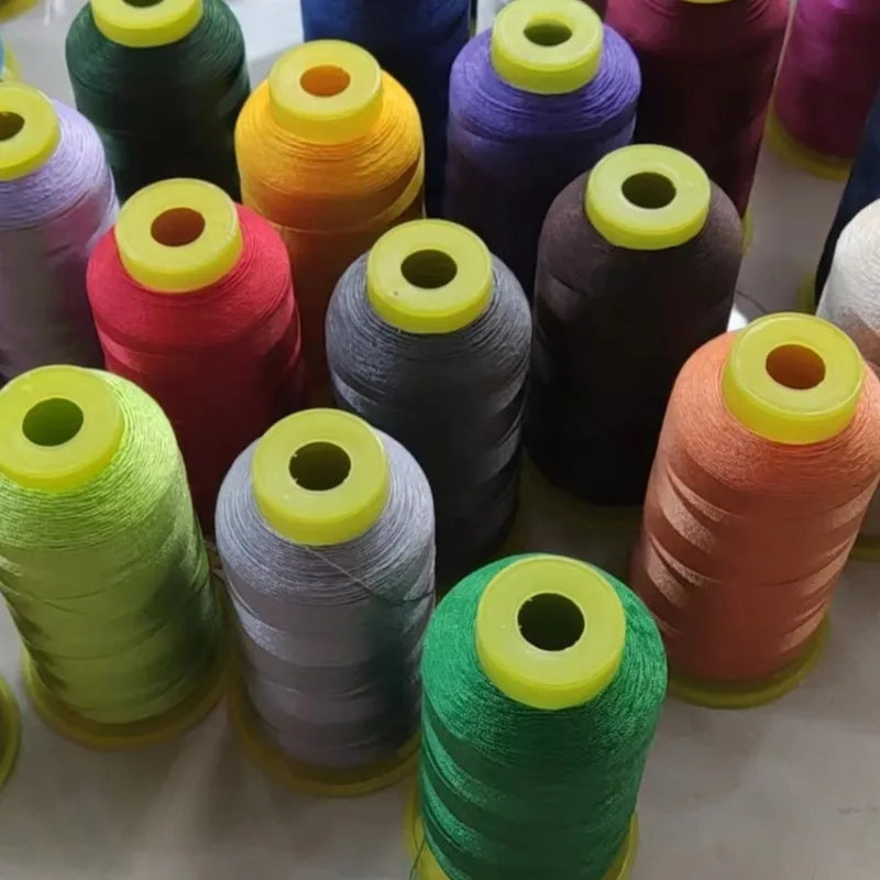 A collection of spools of high tenacity polyester sewing thread in various colors including green, pink, purple, and orange.
