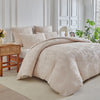 A beige luxury quilt duvet set displayed on a bed with white walls and natural light.