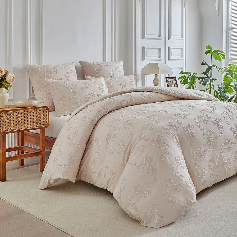 A beige luxury quilt duvet set displayed on a bed with white walls and natural light.