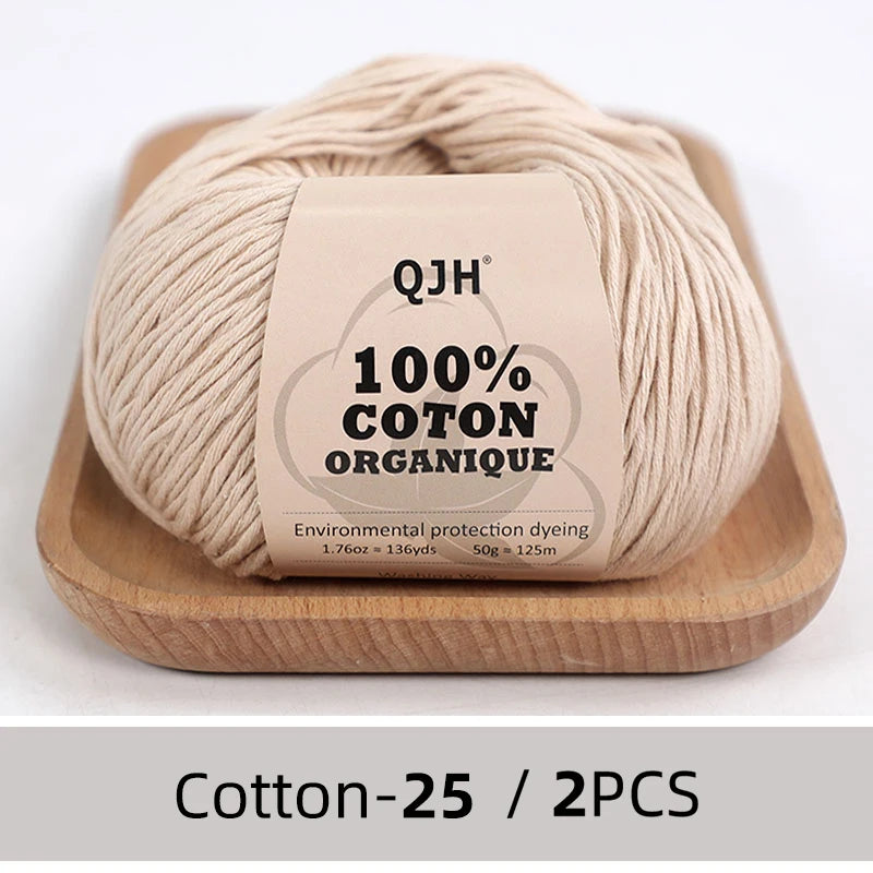 A ball of beige 100% organic cotton yarn labeled QJH with environmental protection dyeing details.