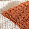 Close-up of a textured, ribbed corduroy throw pillow cover in a warm burnt orange color.