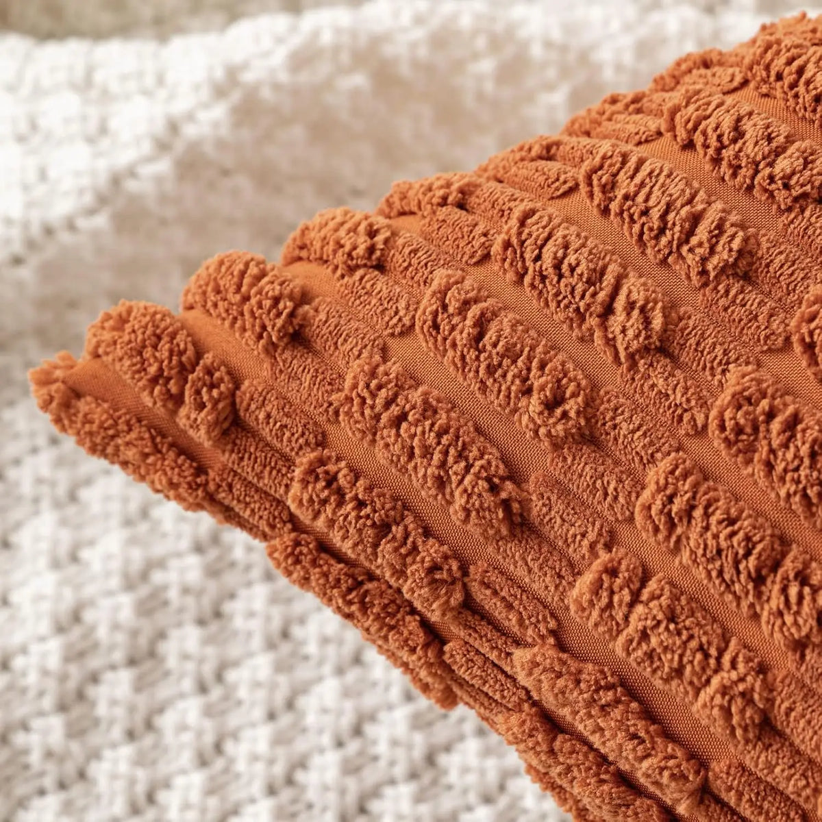 Close-up of a textured, ribbed corduroy throw pillow cover in a warm burnt orange color.