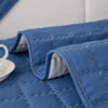 A close-up of a quilted blue anti-slip sofa cover with a plush texture and white stitching.