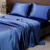 A deep blue satin bedding set featuring a duvet and pillows on a bed.