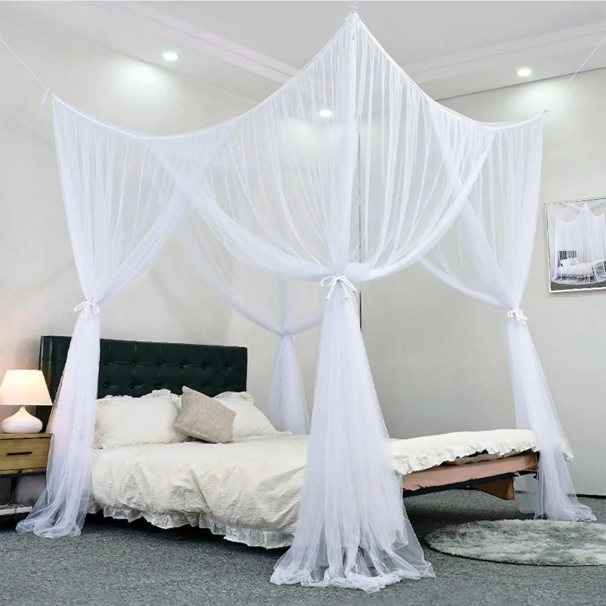 White floor-to-ceiling mosquito net curtains draped over a bed frame in a bright room.