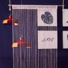 Pink beaded string curtains hanging against a dark blue background with a heart design.