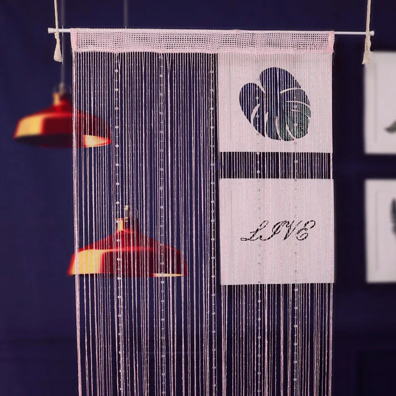 Pink beaded string curtains hanging against a dark blue background with a heart design.