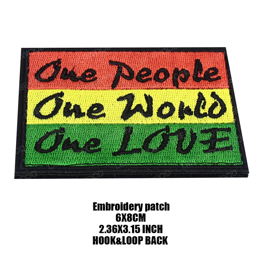 An embroidery patch featuring the text One People One World One LOVE in horizontal stripes of orange, yellow, and green.