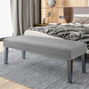 A modern gray velvet bench slipcover with secure straps placed on a light gray striped rug.